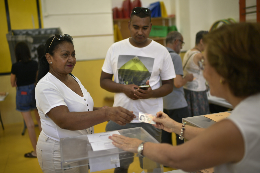 A woman shows her ID as she votes at a polling station in Pamplona, Spain, Sunday July 23, 2023.