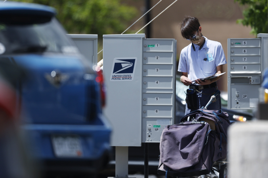 FILE - A mailman wears a face mask while completing his route on May 23, 2020, in downtown Littleton, Colo. Starting Sunday, July 9, 2023, the cost of the first-class "forever" stamps will jump from 63 to 66 cents. The latest price comes just months after forever stamps climbed from 60 to 63 cents in January, following a series of similar increases seen over recent years.