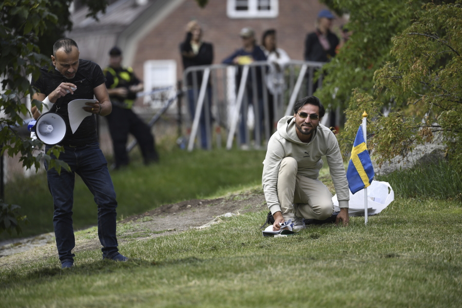 Protestor Salwan Momika kneels next to a Swedish flag outside the Iraqi embassy in Stockholm, Thursday, July 20, 2023, where he plans to burn a copy of the Quran and the Iraqi flag.