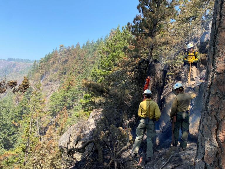 Firefighters work to extinguish a smoking, burned out tree on a steep cliff on Thursday while fighting the Tunnel Five Fire in the Columbia River Gorge.