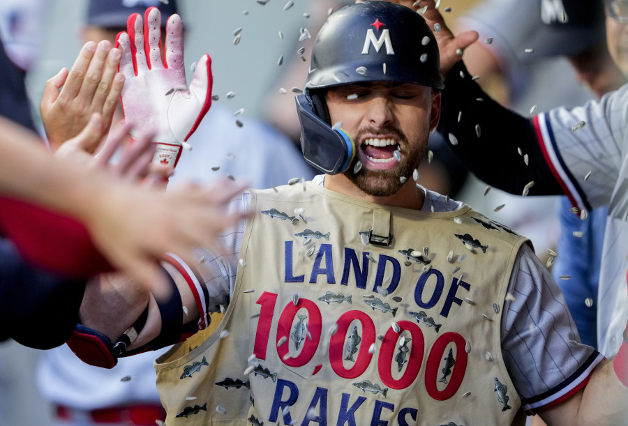 Minnesota Twins' Edouard Julien wears a fishing vest in the dugout as teammates throw sunflower seeds at him to celebrate his solo home run against the Seattle Mariners during the fifth inning of a baseball game, Wednesday, July 19, 2023, in Seattle.