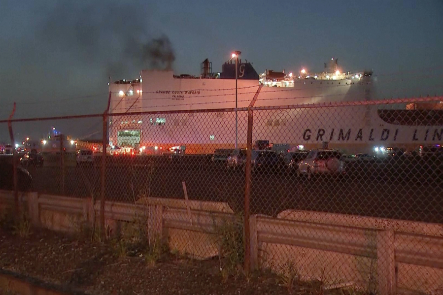 In this image taken from video, smoke rises from a cargo ship early Thursday, July 6, 2023, in the port of Newark, New Jersey. Two firefighters were killed battling the blaze that began when cars caught fire deep inside the ship carrying 5,000 cars at the port, Newark's fire chief said.