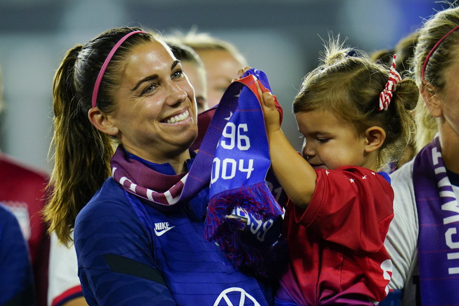 FILE -United States' Alex Morgan holds her daughter, Charlie, as she listens to Cindy Parlow Cone, president of the U.S. Soccer Federation, speak during an event with the federation, U.S. Women's National Team Players Association and the U.S. National Soccer Team Players Association at Audi Field in Washington, Tuesday, Sept. 6, 2022. Morgan says she feels calmer heading into this World Cup and wants to represent mom athletes. She's one of three mothers on this U.S. squad and is often accompanied by 3-year-old daughter Charlie.