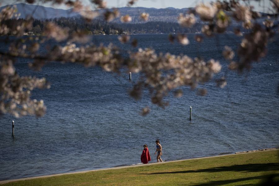 Two children walk Madison Park Beach after going for a dip in the water April 13, 2021.