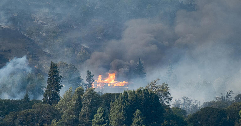 Not all can be saved: A Fire Boss amphibious air tanker dumps 200 gallons of water over the Tunnel 5 Fire. The house in flames (left) and directly beneath the water drop were completely destroyed.