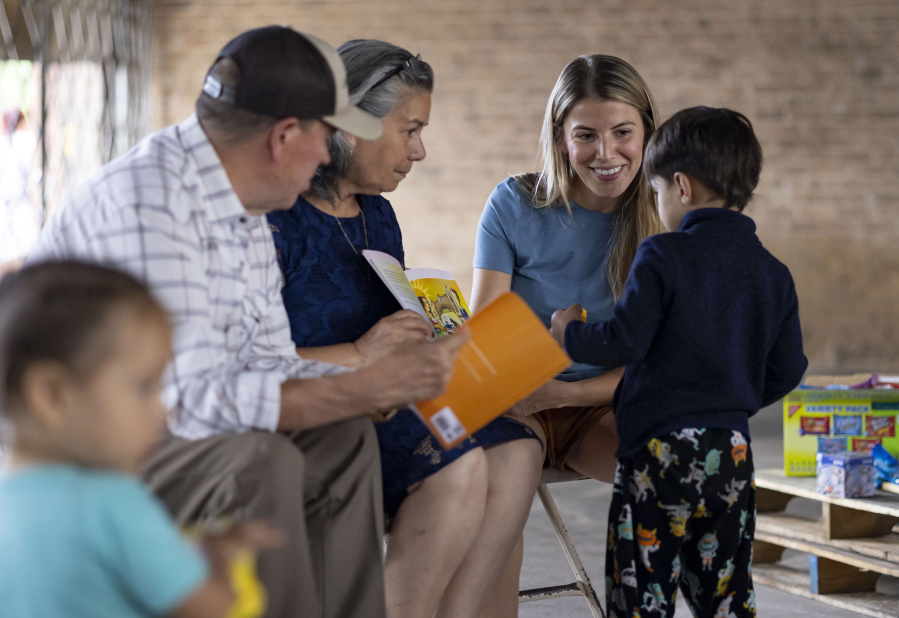 Margarita Qui?ones-Pe?a, joined by her parents, Eduardo and Antonia, reads her children's book to young migrants on July 9 at a Pilsen shelter in Chicago.