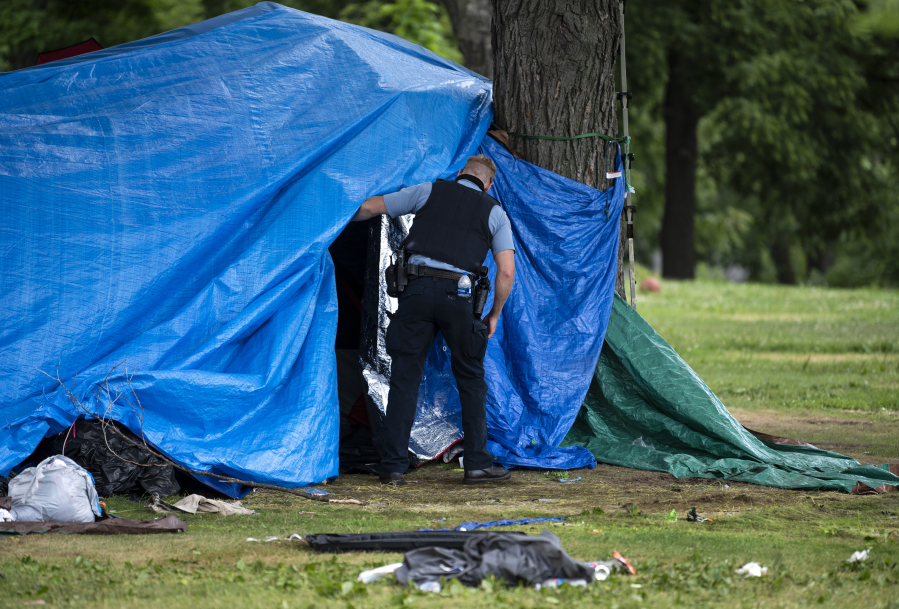 A Minneapolis Police officer checks a structure July 20, 2020, in Powderhorn Park before clearing it to be destroyed as a homeless encampment is cleared on in Minneapolis, Minn.