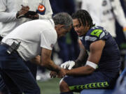 Seattle Seahawks team personnel check out the wrist of wide receiver Jaxon Smith-Njigba during an NFL preseason football game against the Dallas Cowboys, Saturday, Aug. 19, 2023, in Seattle. The Seahawks won 22-14.