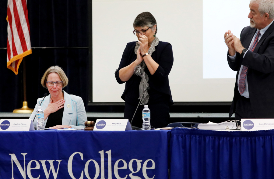 Patricia Okker, left, then president of New College, chokes back tears as newly appointed trustees terminate her during their first meeting in January. New College board chairperson Mary Ruiz, center, and New College general counsel David Smolker applaud her tenure. Okker had said she looked forward to working with the new leaders but never got the chance. (Douglas R.