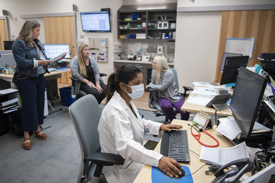 Dr. Neha Didwaniya, foreground center, works at her desk after seeing a patient. She's joined by operations manager Rebecca Hildreth, background from left, medical assistant Abby Pearson and certified nursing assistant Ashlee Harris at Vancouver Clinic's Evergreen Place location. Despite regional health care challenges, Vancouver Clinic has furthered its expansion into Oregon.