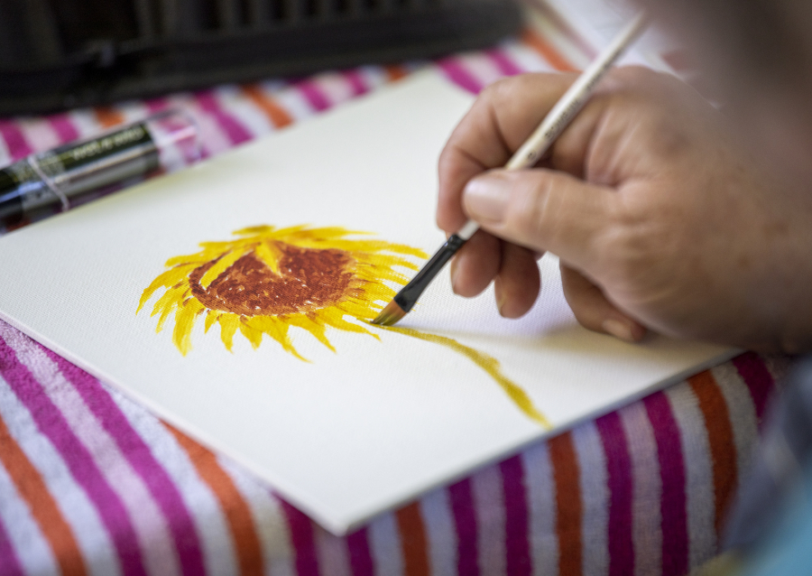 Watercolorist Cheryl Herndon paints a sunflower plucked from her own garden during an outdoor painting event at the O.O. Howard House.