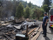 Firefighter Michael Hickey works at the scene Thursday afternoon, Aug. 17, 2023, after a blaze destroyed a primary residence and surrounding structures on the same property near La Center on Wednesday night. The incident sparked a significant brush fire that prompted evacuation warnings well into the north county community.