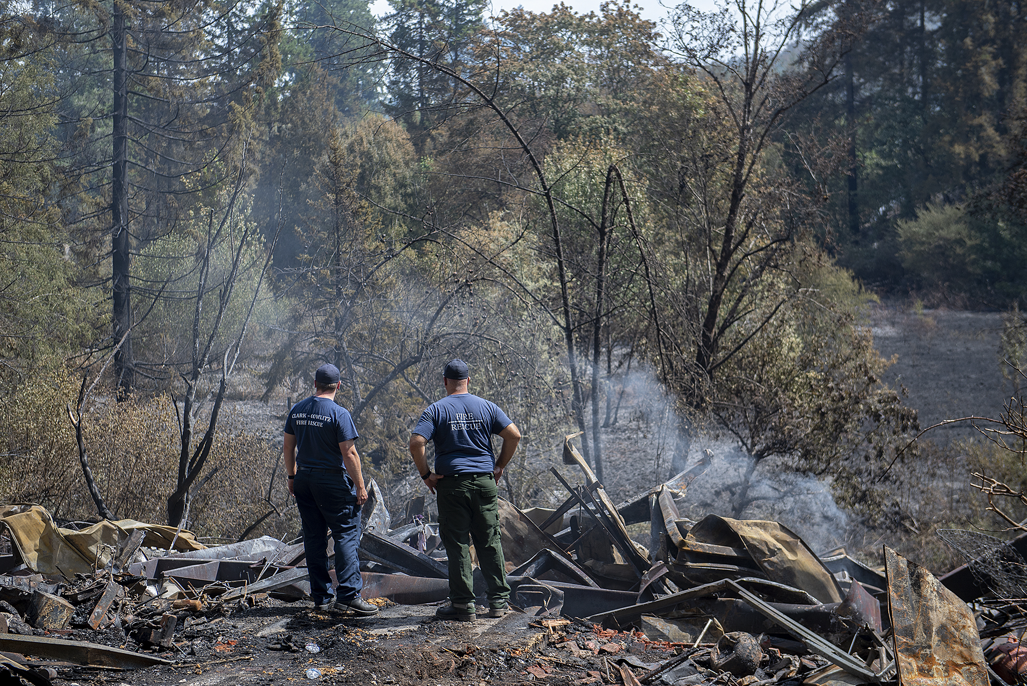 Firefighters Michael Hickey, left, and Joe Talarico survey the scene Thursday afternoon, Aug. 17, 2023, after a blaze destroyed a primary residence and surrounding structures on the same property near La Center on Wednesday night. The incident sparked a significant brush fire that prompted evacuation warnings well into the north county community.