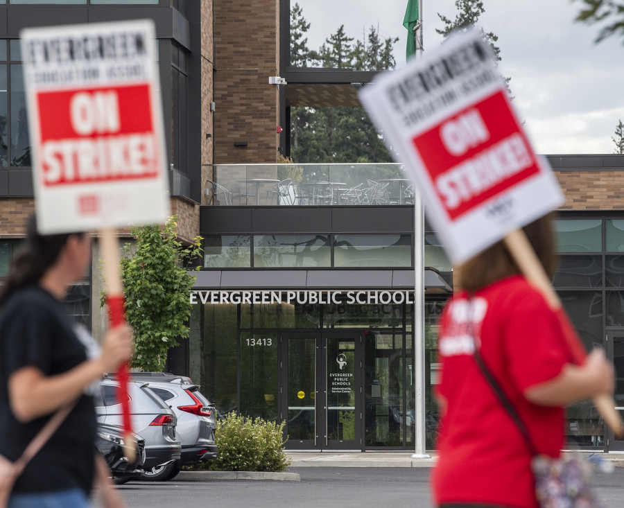 Evergreen Education Association members walk in front of the Evergreen Public Schools building on Tuesday during a sign-making rally at Leroy Haagen Memorial Community Park. Schools are closed Aug. 30 due to the looming strike, according to the Evergreen Public Schools website.