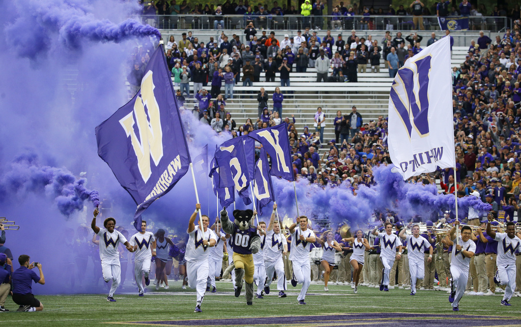 FILE - Washington cheerleaders and Harry, the Husky mascot, set off smoke effects as they lead the team out of the tunnel at Husky Stadium for Washington's home opener, an NCAA college football game against Montana, Saturday, Sept. 9, 2017, in Seattle. Dealing a crushing combination to the Pac-12 on Friday, Aug. 4, 2023, the Big Ten announced Oregon and Washington would be joining the conference next August, and the Big 12 completed its raid of the beleaguered league by adding Arizona, Arizona State and Utah.  (AP Photo/Ted S.
