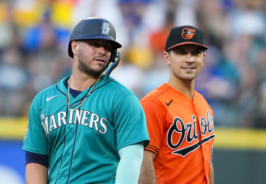 Seattle Mariners' Ty France, left, talks with former teammate Baltimore Orioles second baseman Adam Frazier during the fourth inning of a baseball game, Saturday, Aug. 12, 2023, in Seattle.