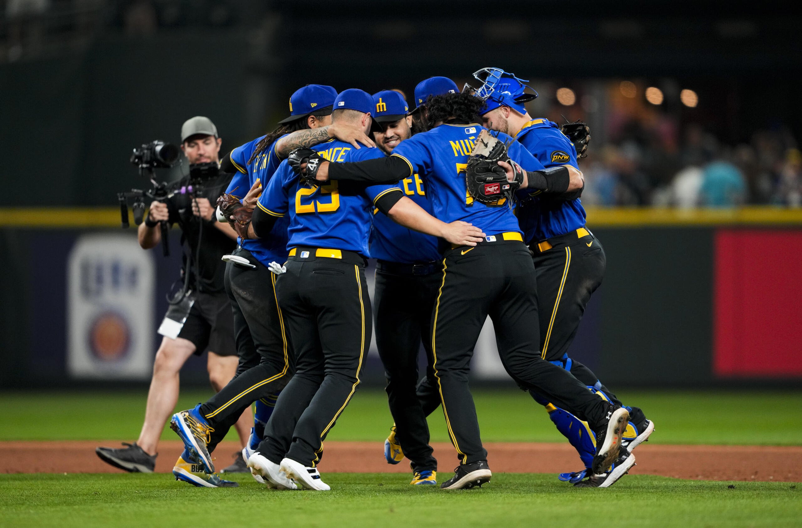 Seattle Mariners, including first baseman Ty France (23), third baseman Eugenio Suárez, center facing, and relief pitcher Andres Munoz (75) dance after the team's win over the Kansas City Royals in a baseball game Friday, Aug. 25, 2023, in Seattle.