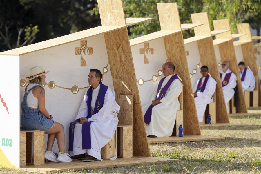 A priest listens to confession in a row of confessionals set up for pilgrims arriving for International World Youth Day on Tuesday at a park in Lisbon, Portugal. Pope Francis will arrive today to attend the event.