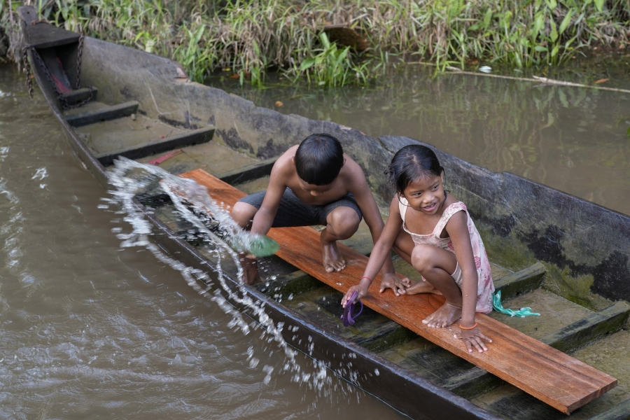 Indigenous Wari' children throw out water from a boat in the Komi Memem River, named Laje in non-Indigenous maps, in Guajara-Mirim, Rondonia state, Brazil, Friday, July 14, 2023.