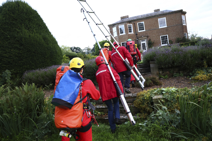 In this photo provided by Greenpeace activists approach the manor house of Britain's Prime Minister Rishi Sunak in Yorkshire, England, Thursday, Aug. 3, 2023. Greenpeace demonstrators have drapped the country estate of British Prime Minister Rishi Sunak in black fabric to protest his announcement this week to expand oil drilling in the North Sea.