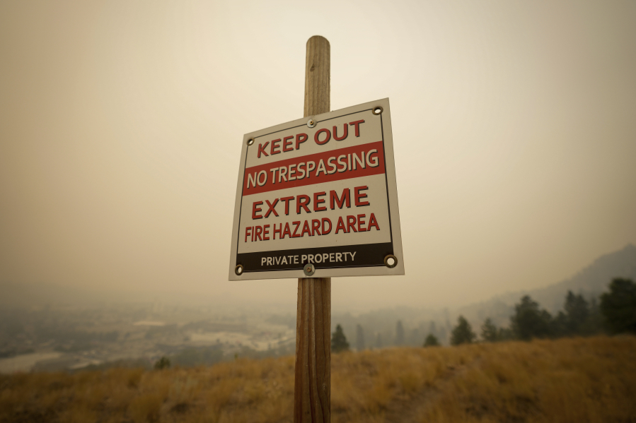 A warning sign about fire risk is seen as smoke from wildfires fills the air, in Kelowna, British Columbia, Saturday, Aug. 19, 2023.