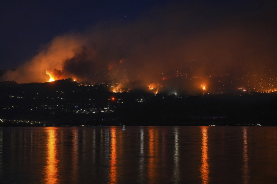 The McDougall Creek wildfire burns on the mountainside above lakefront homes in West Kelowna, Canada on Friday, Aug. 18, 2023.