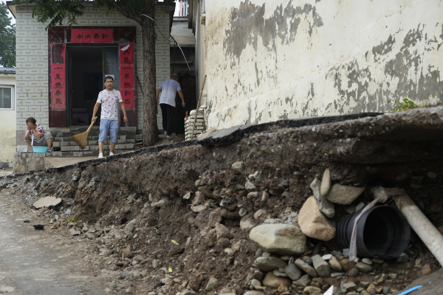Residents try to restore normalcy to their lives near underground pipes exposed after floods sweep through a village on the outskirts of Beijing, Friday, Aug. 4, 2023. Heavy rain and high water levels on rivers in northeastern China were threatening cities downstream on Friday, prompting the evacuation of thousands, although the country appears to have averted the worst effects of the typhoon season battering parts of east Asia.
