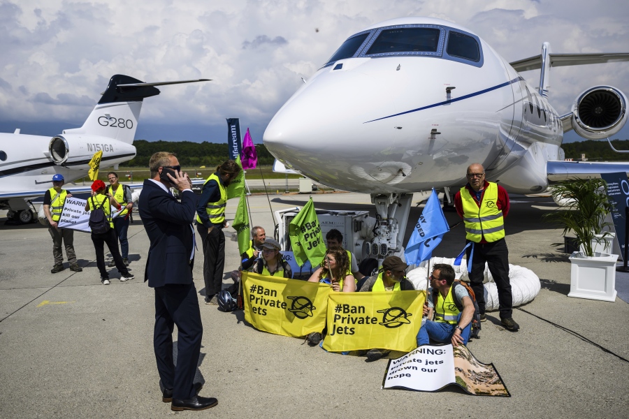 FILE - Environmental activists of Stay Grounded and Greenpeace demonstrate while handcuffing themselves to a plane during the European Business Aviation Convention and Exhibition (EBACE), at the Geneve Aeroport in Geneva, Switzerland, May 23, 2023. Climate activists have spraypainted a superyacht, blocked private jets from taking off and plugged holes in golf courses this summer as part of an intensifying campaign against the emissions-spewing lifestyles of the ultrawealthy.