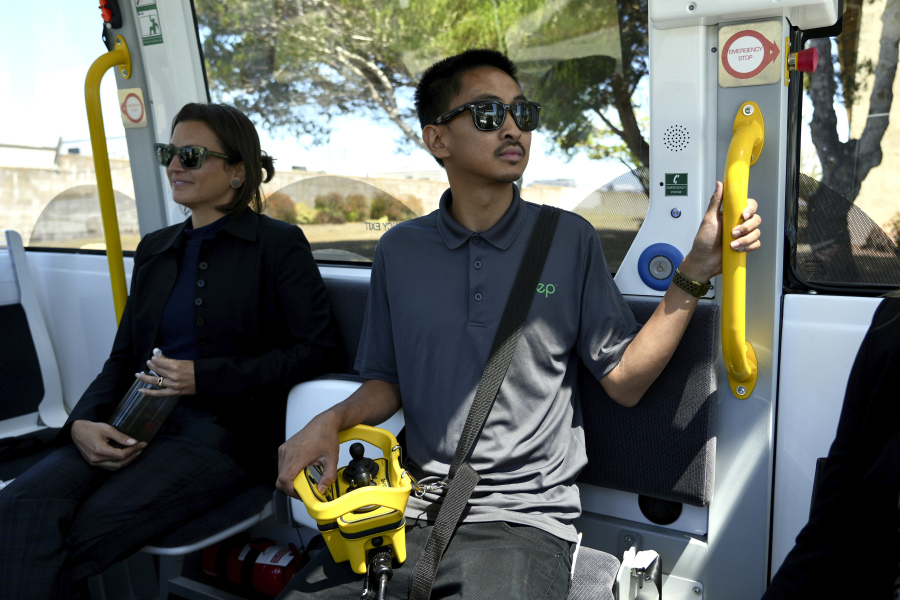 An attendant keeps an eye on the road from inside a driverless shuttle as it transports passengers on San Francisco's Treasure Island on Aug. 16, 2023. He can manually drive the autonomous bus with a handheld controller if necessary. The free bus service was launched less than a week after California regulators approved the controversial expansion of robotaxis on city streets.