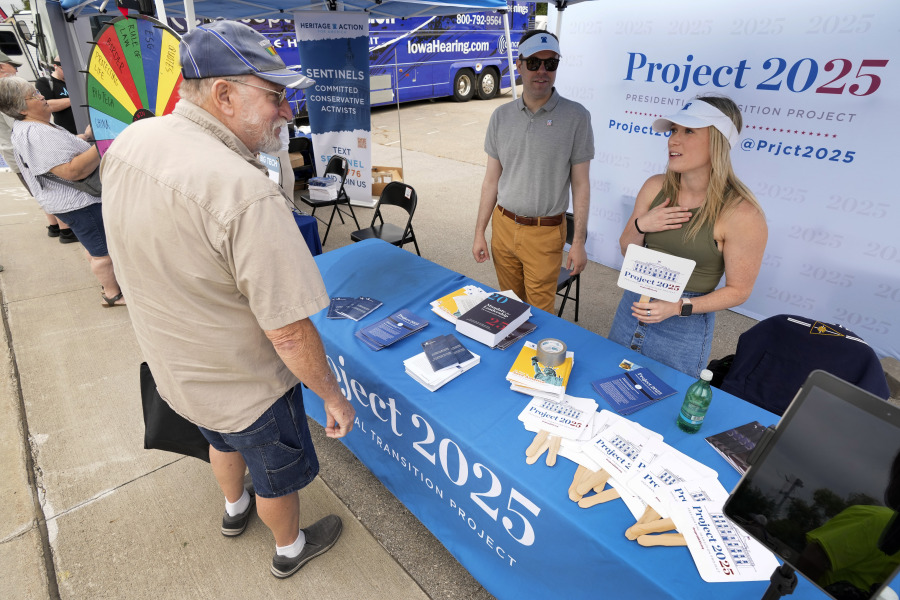 Kristen Eichamer, right, and Spencer Chretien, center, talk to Russ Pinta, left, of Colo, Iowa, at the Project 2025 tent at the Iowa State Fair, Aug. 14, 2023, in Des Moines, Iowa. With more than a year to go before the 2024 election, a constellation of conservative organizations is preparing for a possible second White House term for Donald Trump. The Project 2025 effort is being led by the Heritage Foundation think tank.