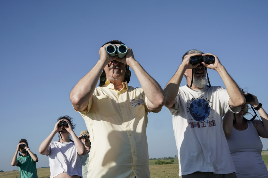 Jason St. Sauver, center, senior manager for education at Spring Creek Prairie Audubon Center, looks through binoculars while leading a grassland bird tour, Tuesday, June 20, 2023, in Denton, Neb. North America's grassland birds are deeply in trouble 50 years after adoption of the Endangered Species Act, with numbers plunging as habitat loss, land degradation and climate change threaten what remains of a once-vast ecosystem. (AP Photo/Joshua A.