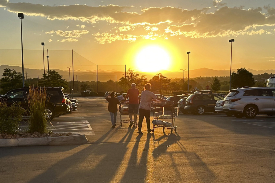 File - Shoppers cast long shadows as they head to their vehicles outside a Costco warehouse on July 11, 2023, in Sheridan, Colo. Although the Federal Reserve has sharply raised interest rates, consumer spending keeps growing at a healthy rate.
