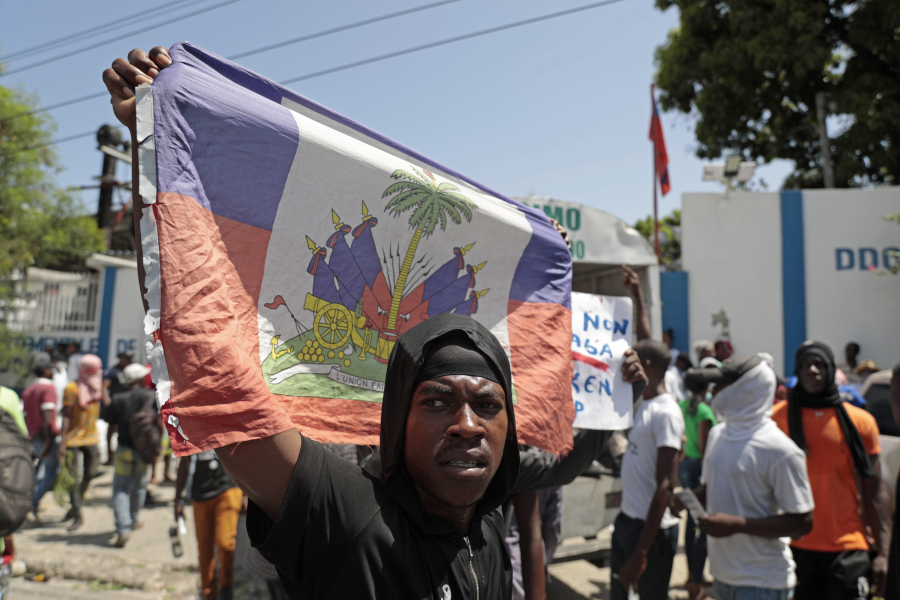 A demonstrator holds up a Haitian flag during a protest against insecurity in Port-au-Prince, Haiti, Monday, Aug. 7, 2023.