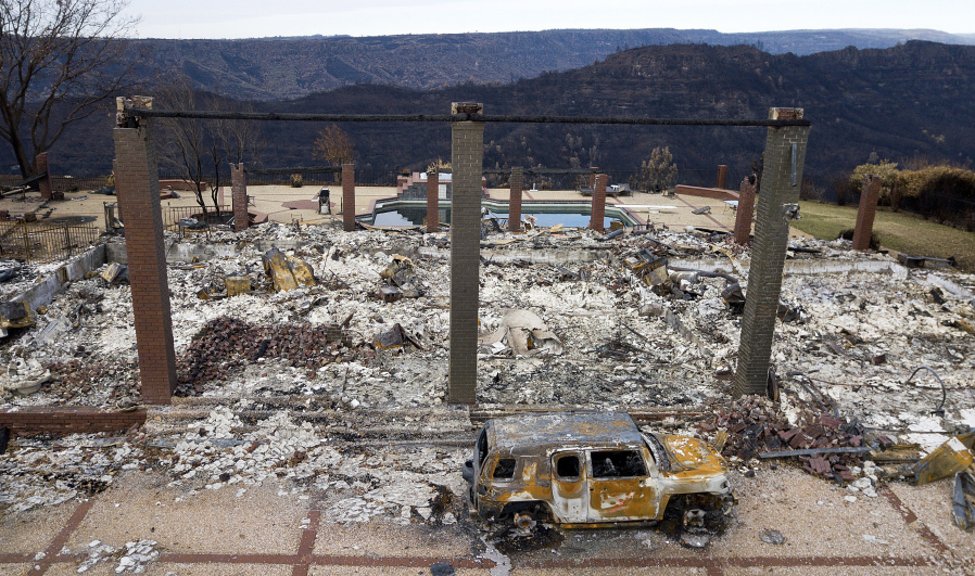 FILE - A vehicle sits in front of a home leveled by the Camp Fire in Paradise, Calif., Dec. 3, 2018. The Camp Fire bears many similarities to the deadly wildfire in Hawaii. Both fires moved so quickly residents had little time to escape.