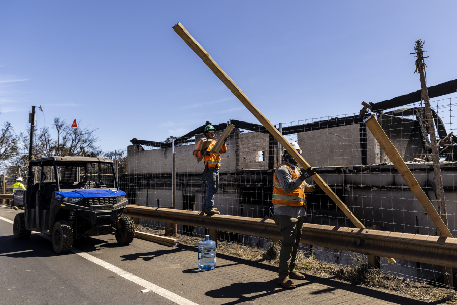 Workers prepare lumber while installing a cover near structures destroyed by the West Maui Fire near Front Street in Lahaina on the island of Maui, Hawaii Thursday, Aug. 17, 2023.