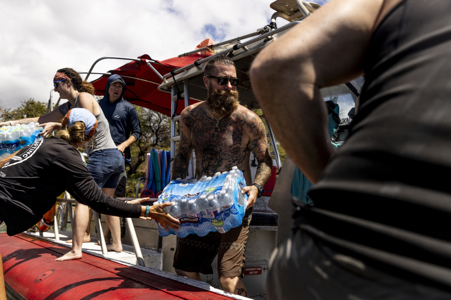 Volunteers load supplies onto a boat for West Maui at the Kihei boat landing, after a wildfire destroyed much of the historical town of Lahaina, on the island of Maui, Hawaii Sunday, Aug. 13, 2023.