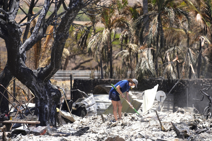A woman digs through rubble of a home destroyed by a wildfire on Friday, Aug. 11, 2023, in Lahaina, Hawaii.