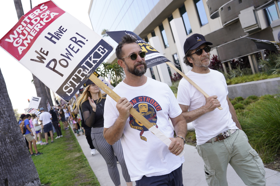 Actors Noah Wyle, left, and Leland Orser walk on a picket line outside Netflix studios on Monday, Aug. 14, 2023, in Los Angeles. The Hollywood writers strike passed the 100-day mark as the film and television industries remain paralyzed by dual actors and screenwriters strikes.