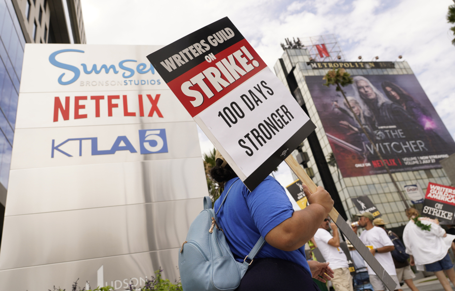 A picketer carries a sign outside Netflix studios on Wednesday, Aug. 9, 2023, in Los Angeles. The Hollywood writers strike reached the 100-day mark today as the U.S. film and television industries remain paralyzed by dual actors and screenwriters strikes.