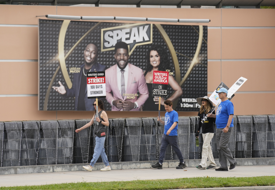 Picketers walk past an advertisement for the Fox Sports television show "Speak" outside Fox studios on Monday, Aug. 14, 2023, in Los Angeles. The Hollywood writers strike passed the 100-day mark as the film and television industries remain paralyzed by dual actors and screenwriters strikes.