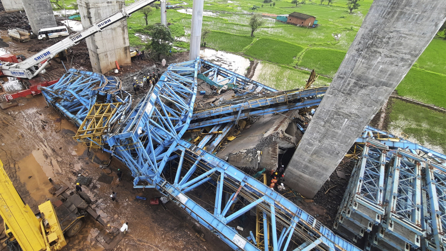 People search among the debris after a huge crane collapsed at a highway construction site at Shahpur Sarlambe village, Thane District, Maharashtra state, India, Tuesday, Aug.1, 2023. More than a dozen workers were killed in the accident.