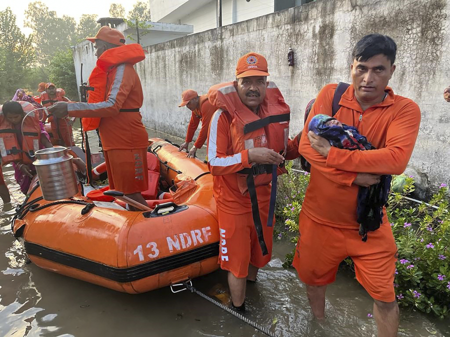 In this photo made available by the National Disaster Response Force (NDRF) on Aug. 15, 2023, an NDRF personnel carries an infant to safety in flood-affected Himachal Pradesh state, India. Heavy monsoon rains triggered floods and landslides in India's Himalayan region, leaving at least 70 people dead and many others trapped.