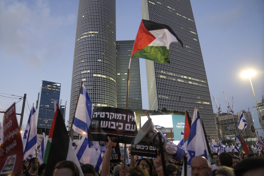 FILE - Demonstrators wave the Israeli and Palestinian flags during a protest against plans by Prime Minister Benjamin Netanyahu's government to overhaul the judicial system, in Tel Aviv, Israel, Saturday, July 22, 2023. Israel is being rocked by a wave of mass protests calling to uphold the country's democracy. But the cries for democracy lack any clear message of opposition to Israel's rule over millions of Palestinians, exposing a contradiction that has been coursing through the demonstrations.