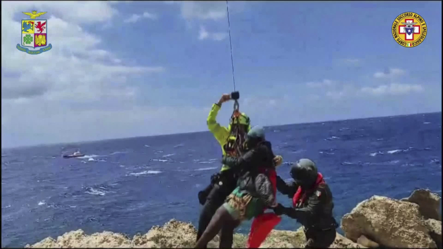 In this picture taken from video distributed on Sunday, Aug. 6, 2023 by the Italian Alpine Rescue squads, a migrant stranded on a rocky reef on the tiny Italian southern island of Lampedusa, Sicily is pluck to safety by helicopter.