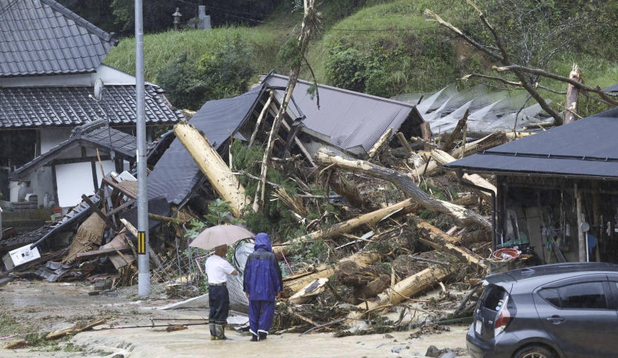 People stand by a mudslide site following a storm in Ayabe, Kyoto prefecture, western Japan Tuesday, Aug. 15, 2023. A strong tropical storm lashed central and western Japan with heavy rain and high winds Tuesday, causing flooding and power blackouts and paralyzing air and ground transportation while many people were traveling for a Buddhist holiday week.