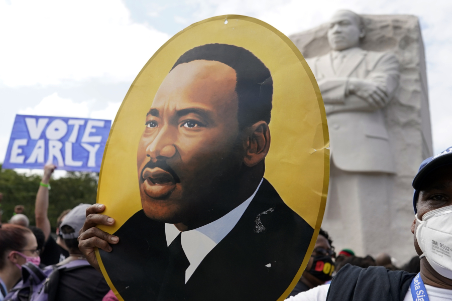 FILE - A man holds a portrait of the Rev. Martin Luther King, Jr., at the Martin Luther King Jr. Memorial during the March on Washington, Friday Aug. 28, 2020, in Washington.