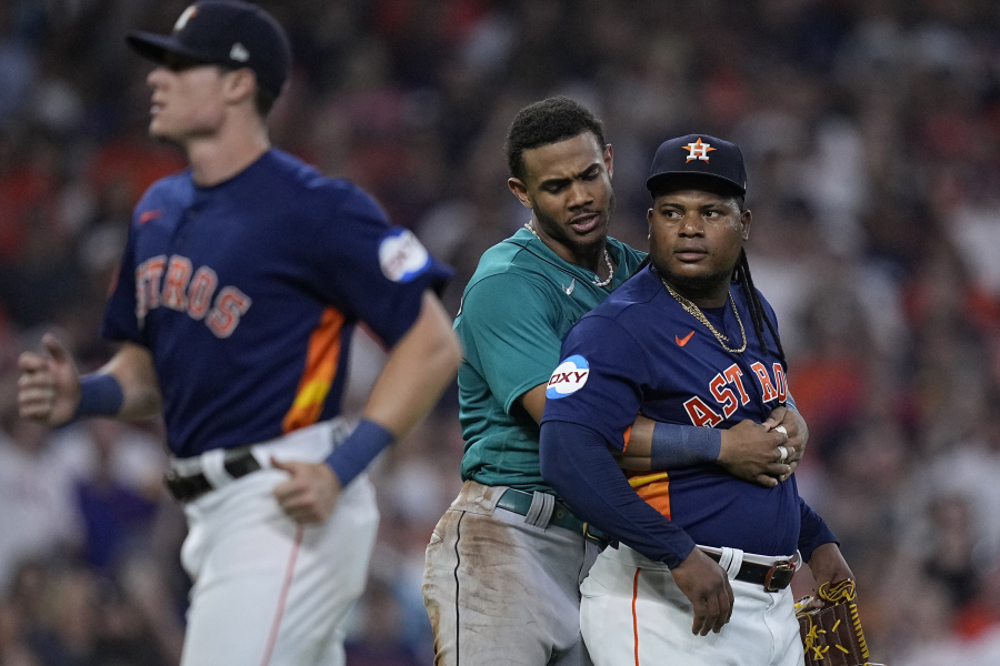 Seattle Mariners' Julio Rodriguez, center, pushes Houston Astros starting pitcher Framber Valdez, right, away from home plate after he hit Mariners' Jose Caballero, causing the benches to clear during the fifth inning of a baseball game, Saturday, Aug. 19, 2023, in Houston. (AP Photo/Kevin M.