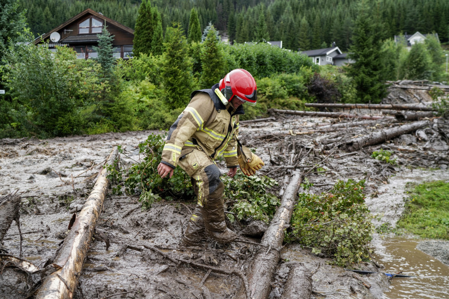 A rescue worker climbs over tree trunks after a mudslide has hit several residential buildings in Bagn in Valdres, Norway, Tuesday, Aug. 8, 2023. Officials in northern Europe are warning people to stay inside as stormy weather batters the region. Storm Hans has cancelled ferries, delayed flights, flooded streets and injured people. Norwegian authorities expected "extremely heavy rainfall" on Tuesday.