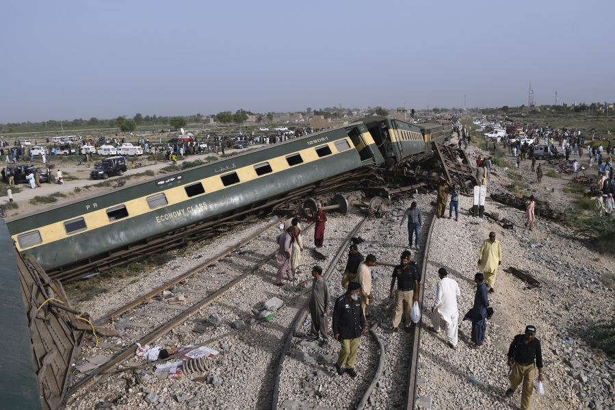Police officers and local residents gather at the site of a passenger train derailed near Nawabshah, Pakistan, Sunday, Aug. 6, 2023. Railway officials say some passengers were killed and dozens more injured when a train derailed near the town of Nawabshah in southern Sindh province.