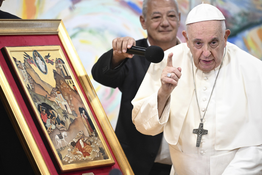 Pope Francis is helped with a microphone by Scholas Occurrentes' President Jose Maria del Corral, left, as he makes remarks about a painting depicting the parable of the 'good Samaritan' during a meeting with members of the Scholas Occurrentes community of young people, an International educational movement created by Pope Francis himself, in Cascais, 25 kilometers south of Lisbon, Thursday, Aug. 3, 2023. Francis gave the final brushstroke to the 3 km mural that the community has been working on and that is the result of the work of more than two thousand people.